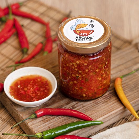 A jar of Arcade Fish Soup chilli sauce with fresh red chillies
